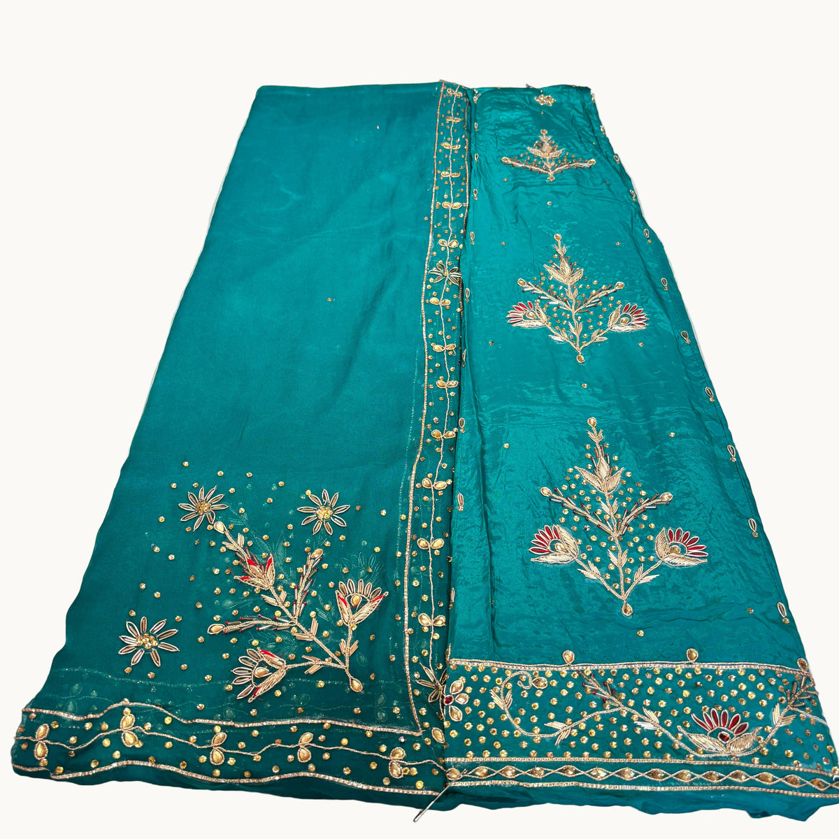 Teal fabric with gold embroidery on a white surface