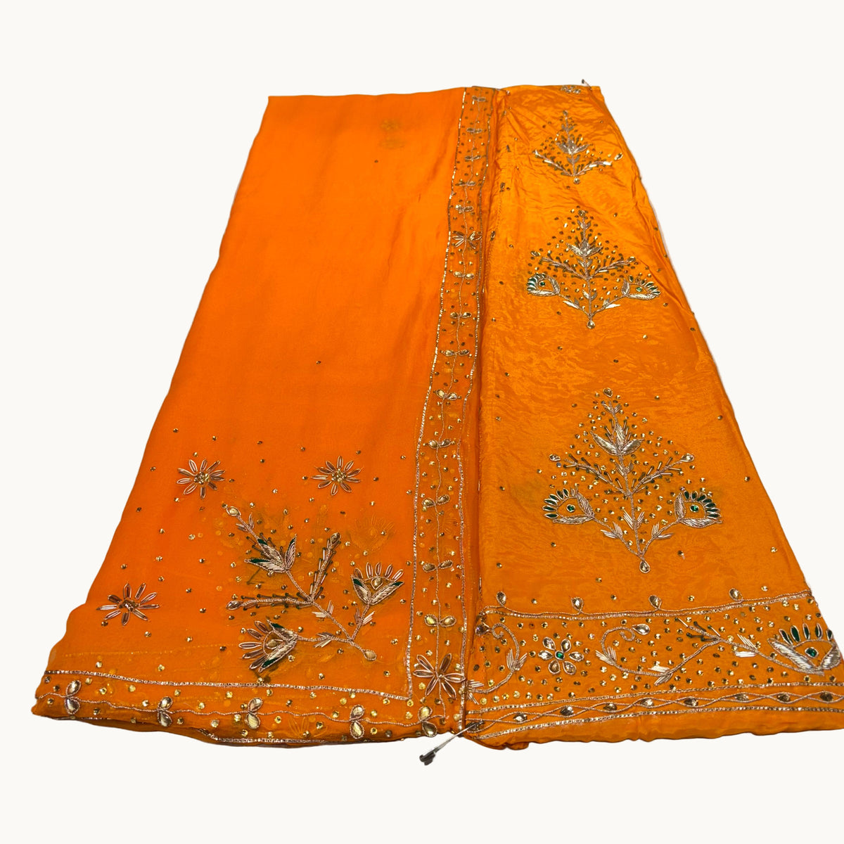 Orange fabric with gold embroidery on a light gray surface