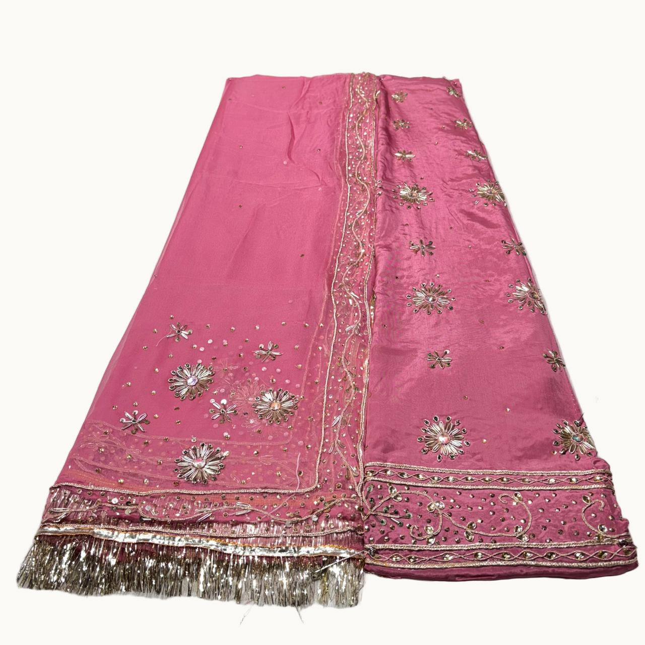 Pink embroidered fabric with gold details on a white surface