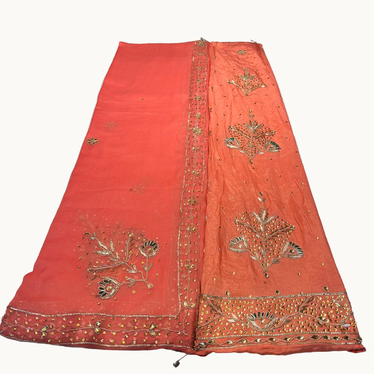 Orange fabric with gold embroidery on a light gray background