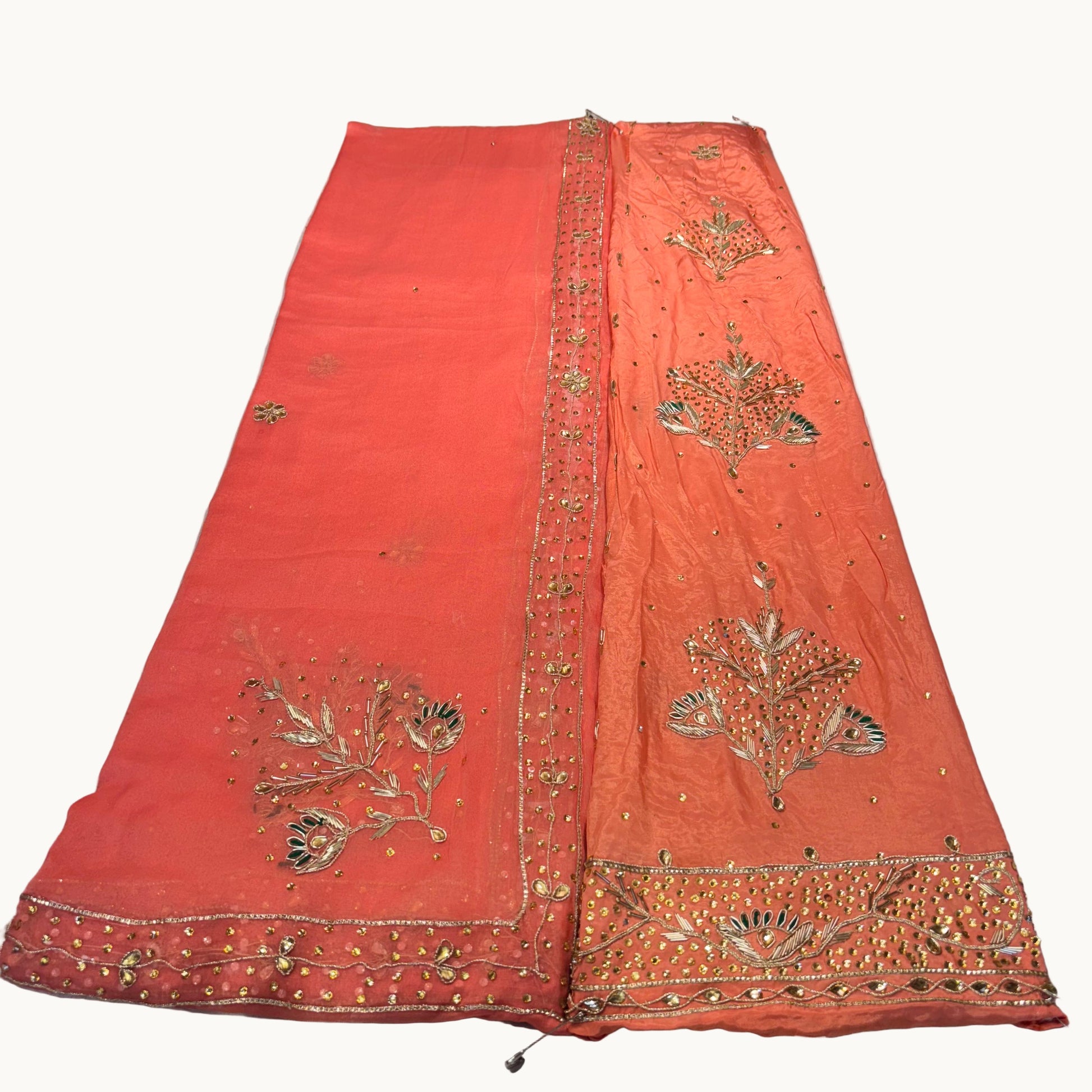 Orange fabric with gold embroidery on a light gray background
