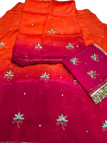 Rani orange Rajputi poshak fabric set, orange shading into rani pink, with sequin flower butti and a folded rani pink odhni with gold fringe