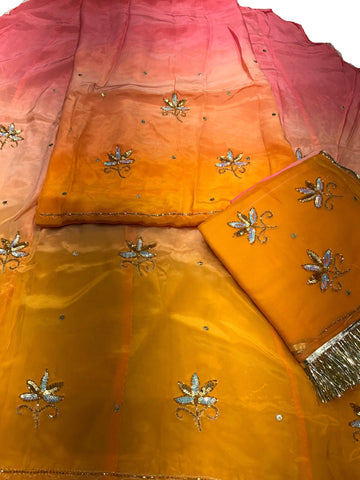 Pink and yellow Rajputi poshak fabric set, pink shading through peach to mustard, with sequin flower butti and a mustard yellow odhni with fringe