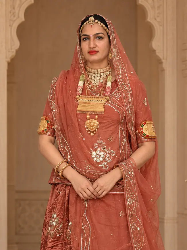 Rust orange kurti with a large zardozi flower at the centre front, pure odhni with zardozi border draped over the head