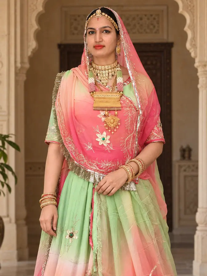 Pink kanchli with zari leaf vines and a stone-centred flower, green sleeves, and the pink-green odhni over the head with a zari edge and gold fringe