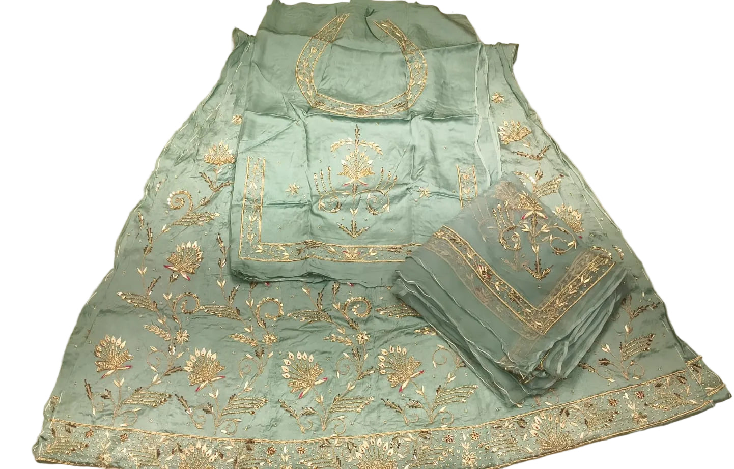 Teal embroidered traditional outfit on a white bedspread