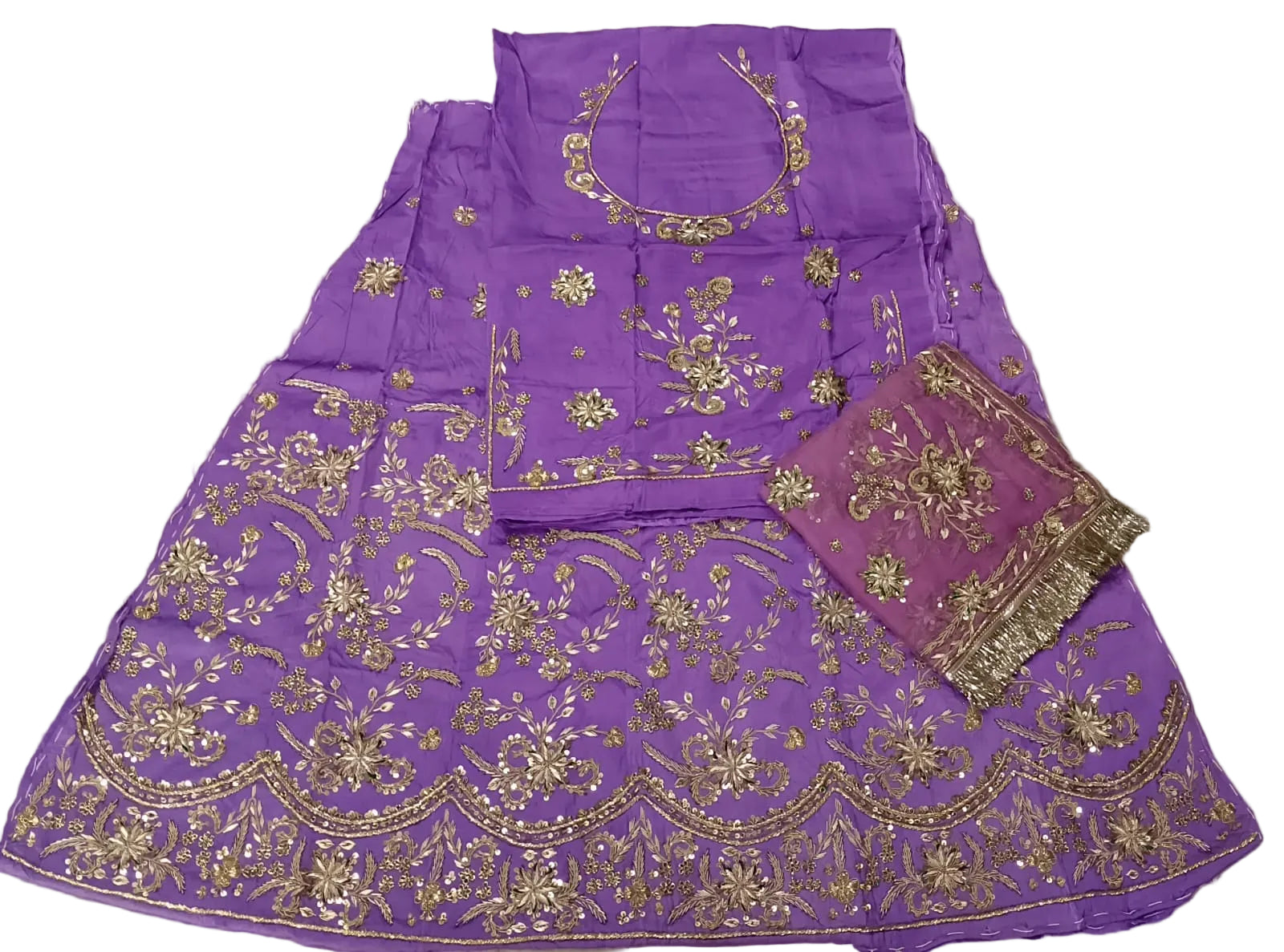Purple traditional outfit with gold embroidery on a beige surface