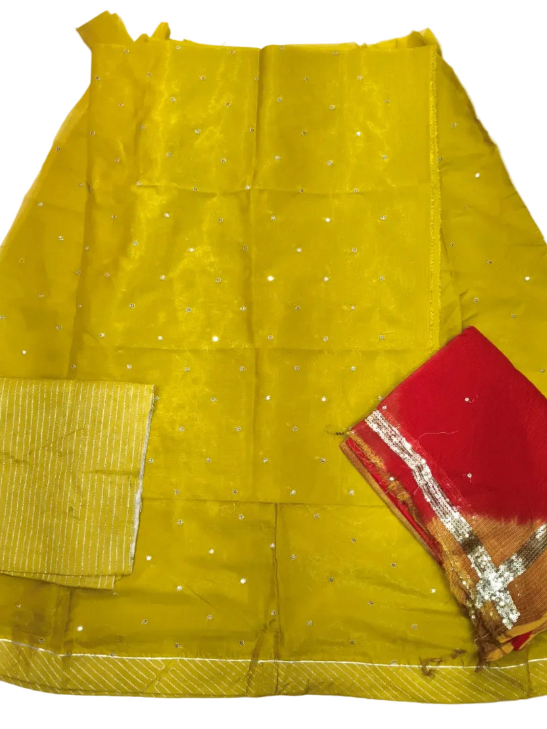 A folded yellow saree with small silver mirror work dots, a red border, and a red blouse piece with gold zari detailing, laid out on a white sheet.