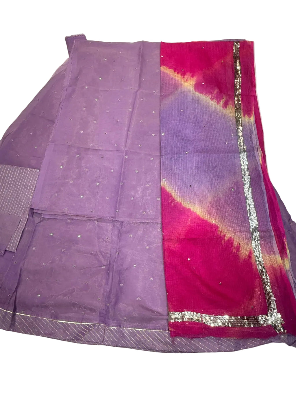 A folded purple saree with a vibrant magenta-pink border featuring a tie-dye pattern and silver zari embroidery, laid flat on a white fabric background.