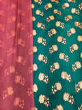 A close-up of a fabric textile with a vertical split design: the left side is dusty pink with matching floral motifs, and the right side is teal green with larger gold floral brocade patterns.