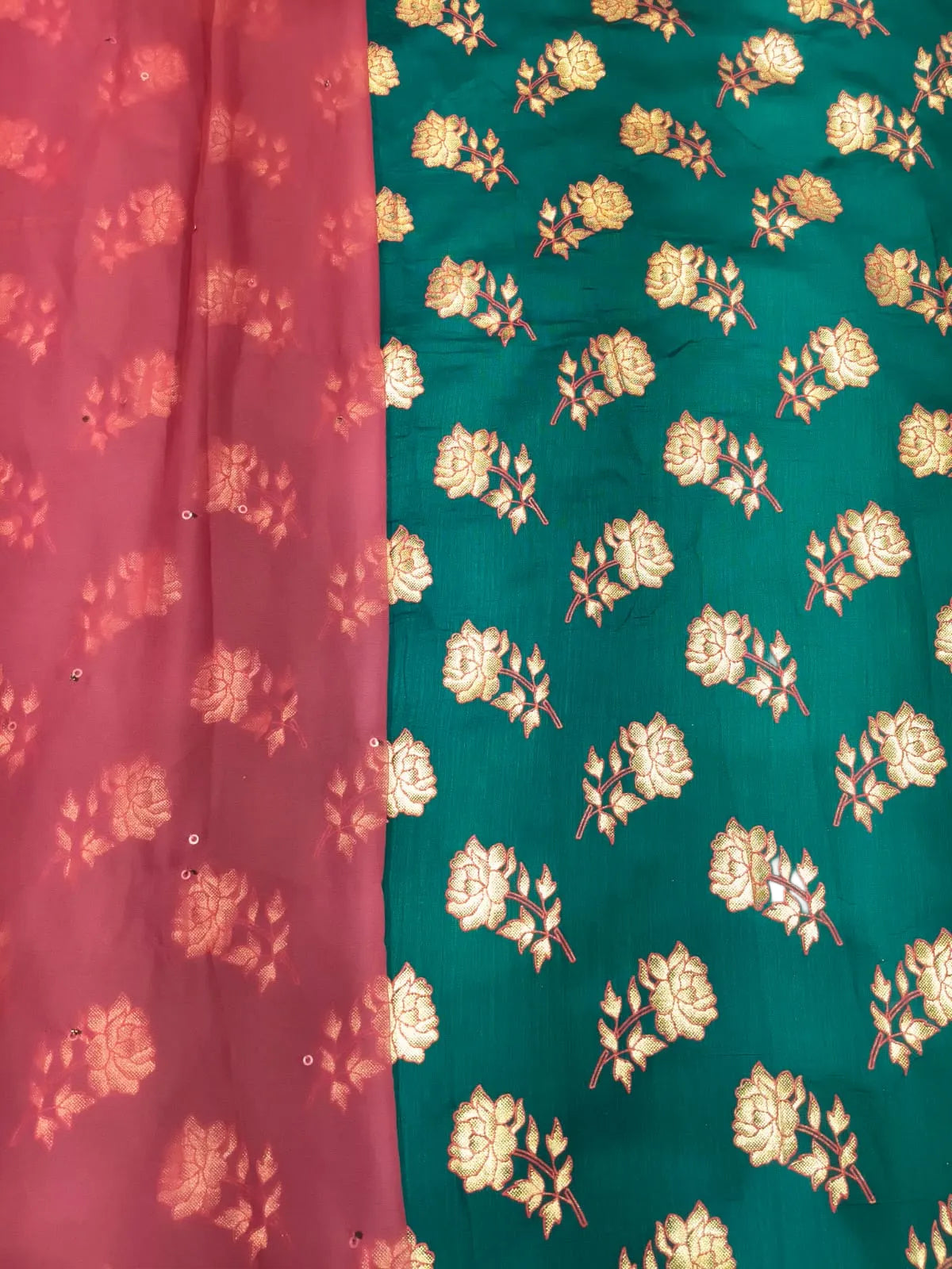 A close-up of a fabric textile with a vertical split design: the left side is dusty pink with matching floral motifs, and the right side is teal green with larger gold floral brocade patterns.
