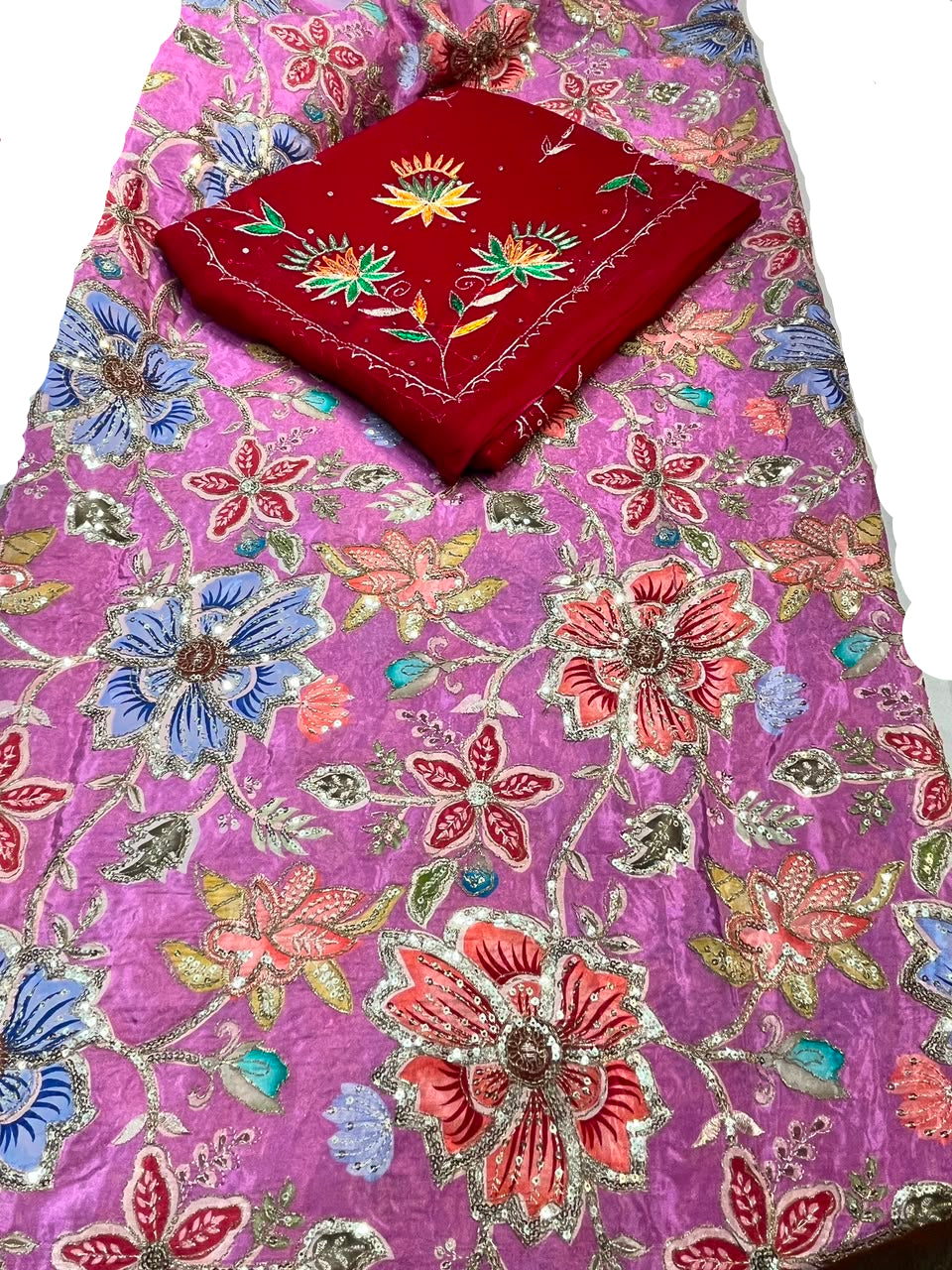 A pink fabric with colorful floral embroidery and metallic silver detailing, folded with a red embroidered fabric piece on top.