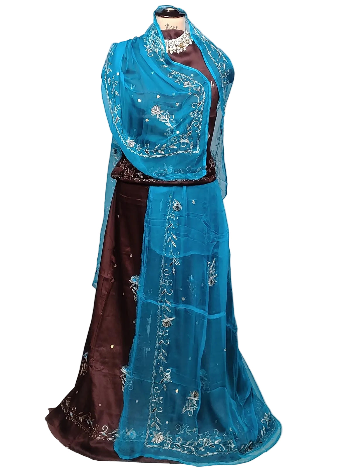 A traditional Indian outfit displayed on a mannequin, featuring a dark brown skirt, a teal blue embroidered blouse, and a matching teal blue dupatta draped over the shoulders.