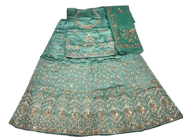 A mint green traditional ethnic garment laid flat on a white fabric background, featuring extensive gold zari embroidery and mirror work.