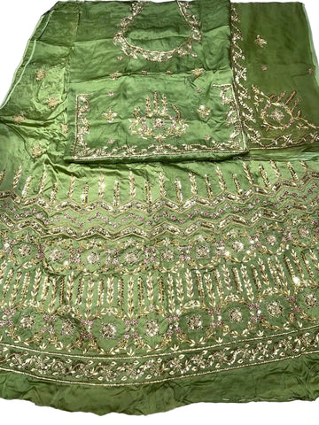 Green embroidered fabric set laid flat on a white surface, featuring ornate metallic gold and pink mirror work embroidery with floral and geometric patterns.