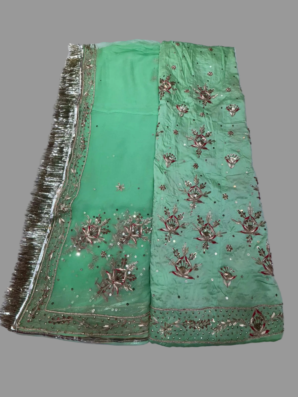 Green embroidered fabric with gold detailing on a white background