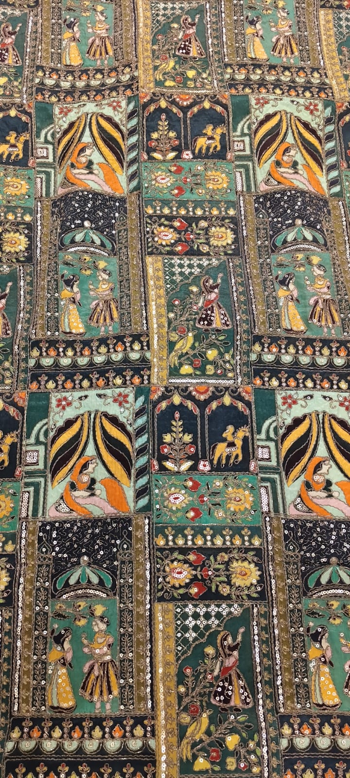 Decorative textile with intricate patterns and figures on a black background