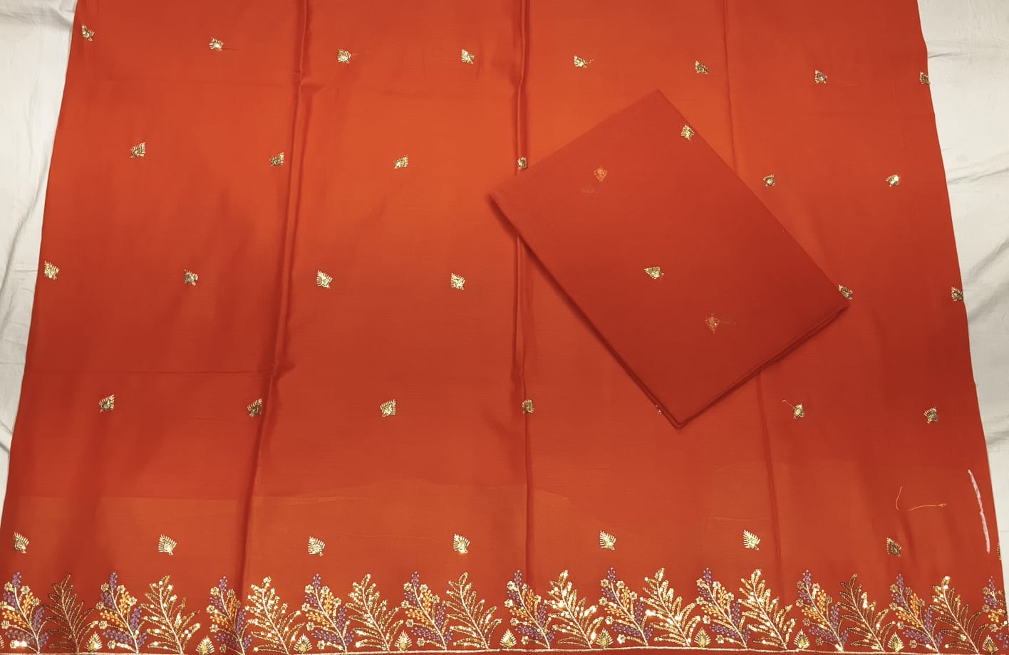 Red fabric with gold embroidery on a white background