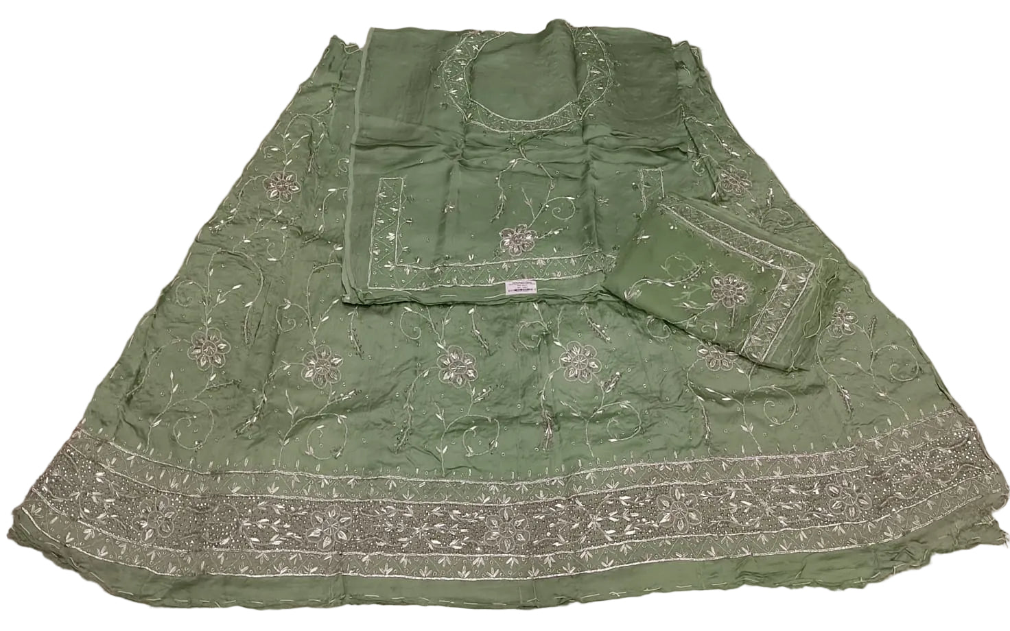 Green traditional outfit with embroidery on a beige fabric background