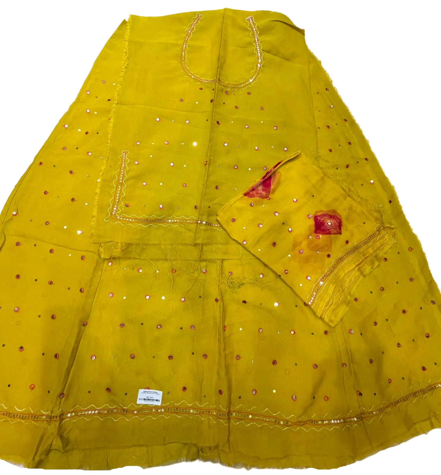 A bright yellow traditional dress material laid flat on a white surface, featuring scattered small red and silver mirror work dots, gold embroidered borders, and a matching yellow fabric piece with red accents.