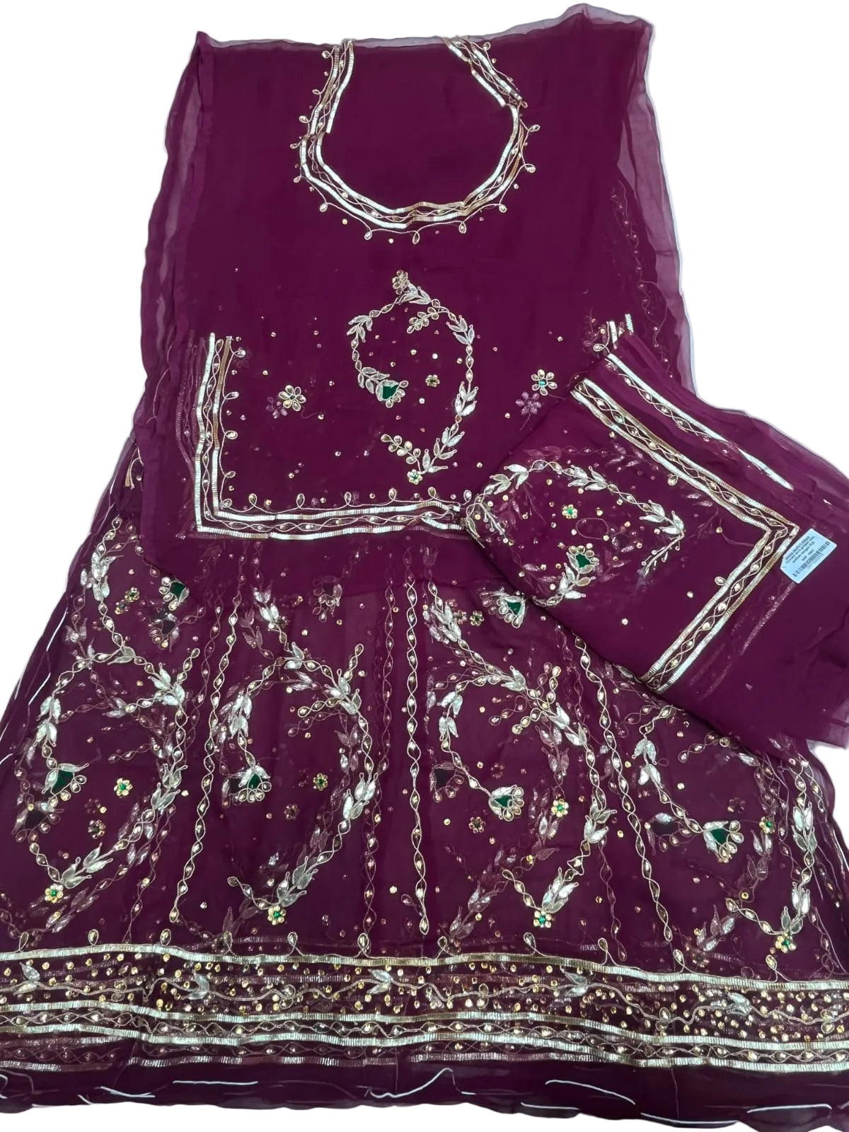 A deep magenta purple traditional rajputi dress set with intricate gold and silver embroidery, displayed flat on a white fabric background. The set includes a kurta, a flared skirt, and a dupatta.