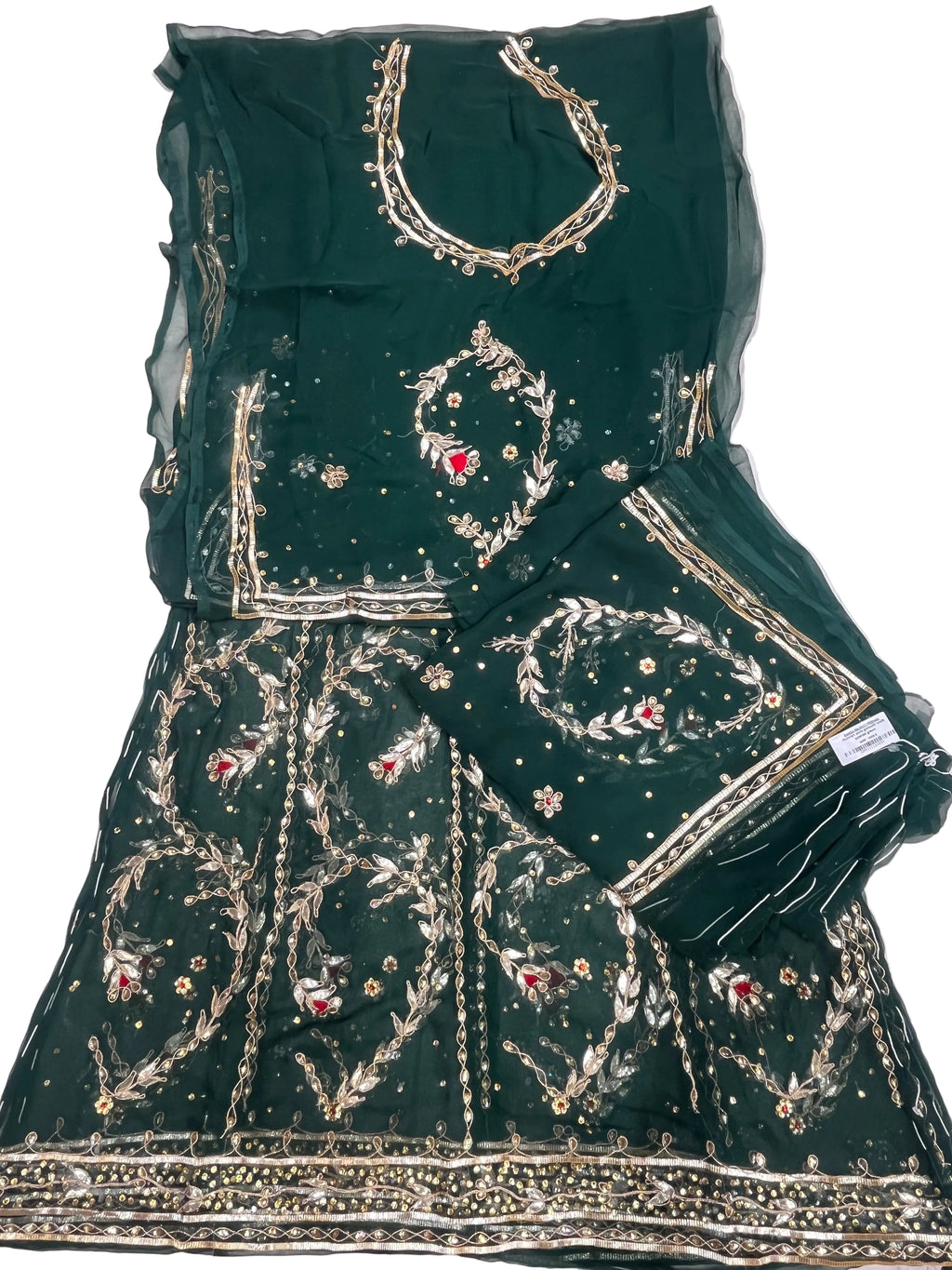 A dark green embroidered traditional rajputi outfit laid flat on a white fabric surface, featuring a flared skirt or dupatta piece with extensive gold embroidery, beadwork, and small red floral accents, plus a matching sheer green blouse piece with gold neckline detailing.