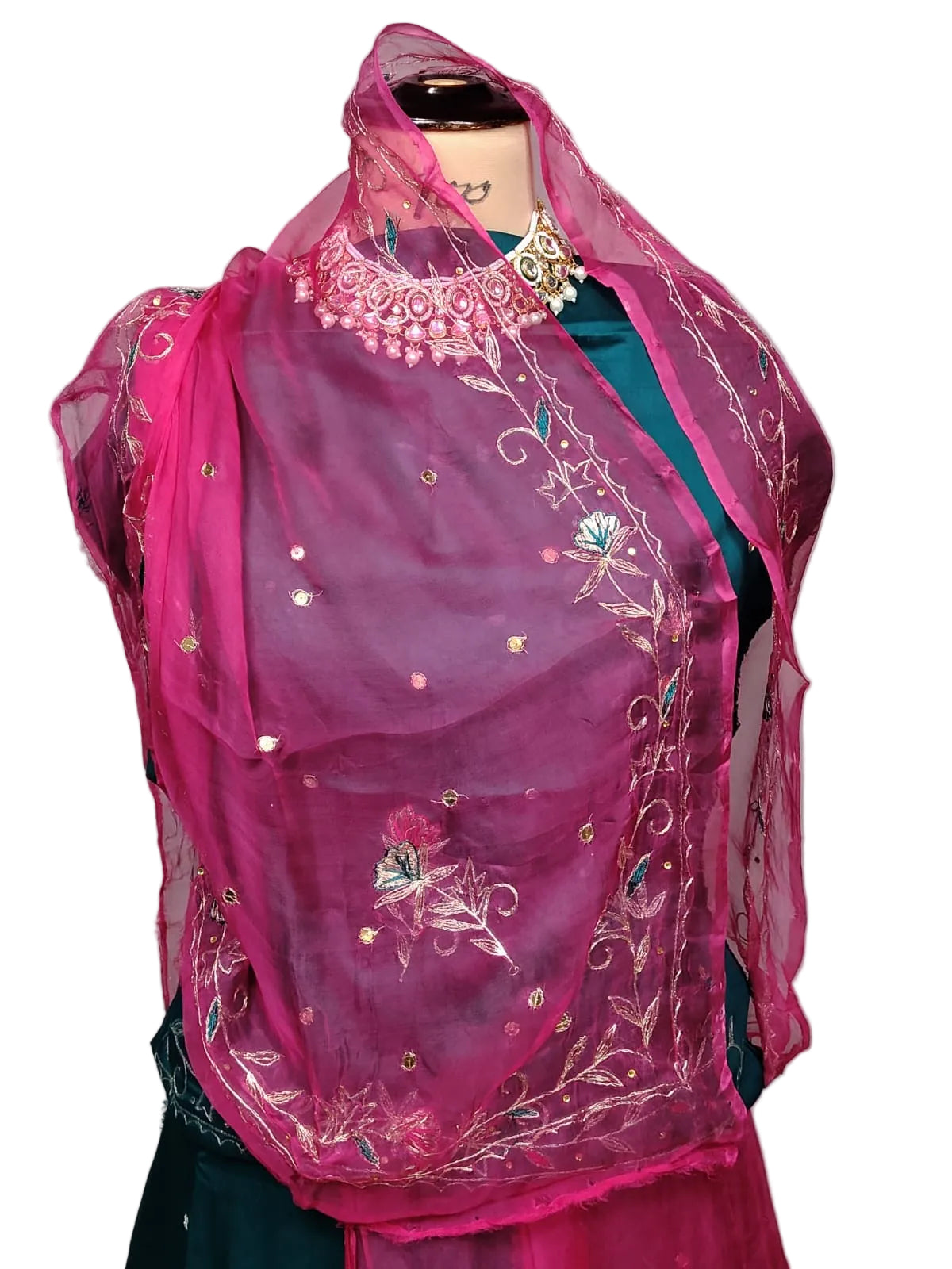 A vibrant magenta pink embroidered dupatta draped over a dark teal blouse on a mannequin, set against a plain gray background.