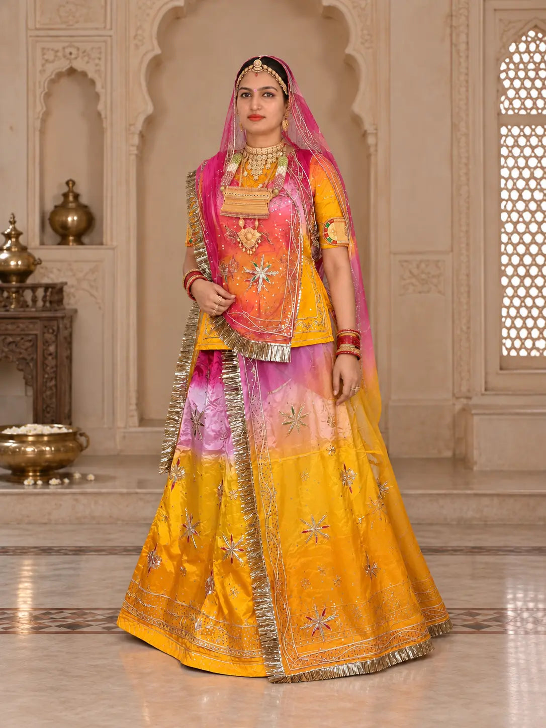 Yellow pink rajputi poshak full set with zardozi stars on the shaded lehenga and a pink Thakurji odhni draped over the head