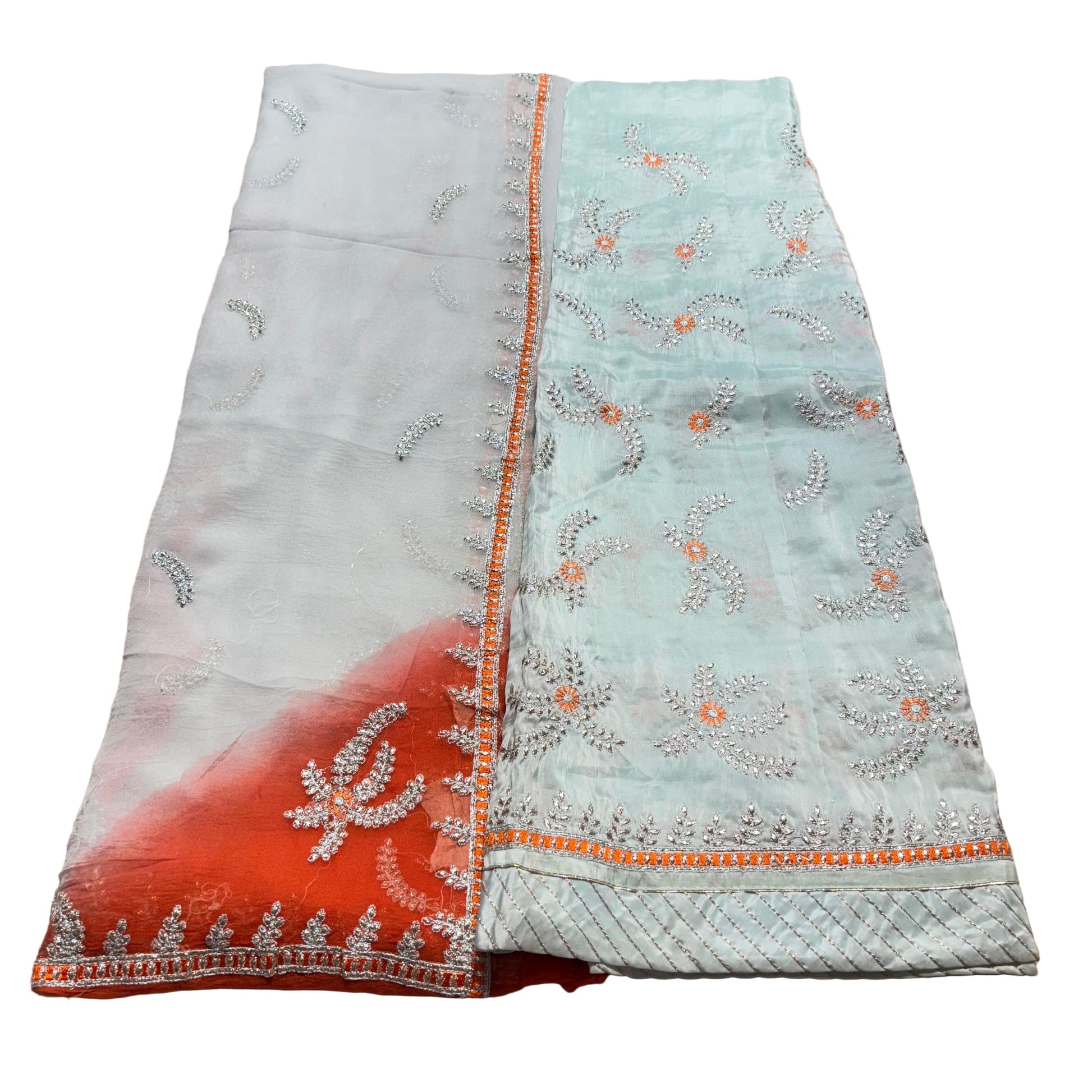 Light blue fabric with intricate patterns and orange accents on a beige surface