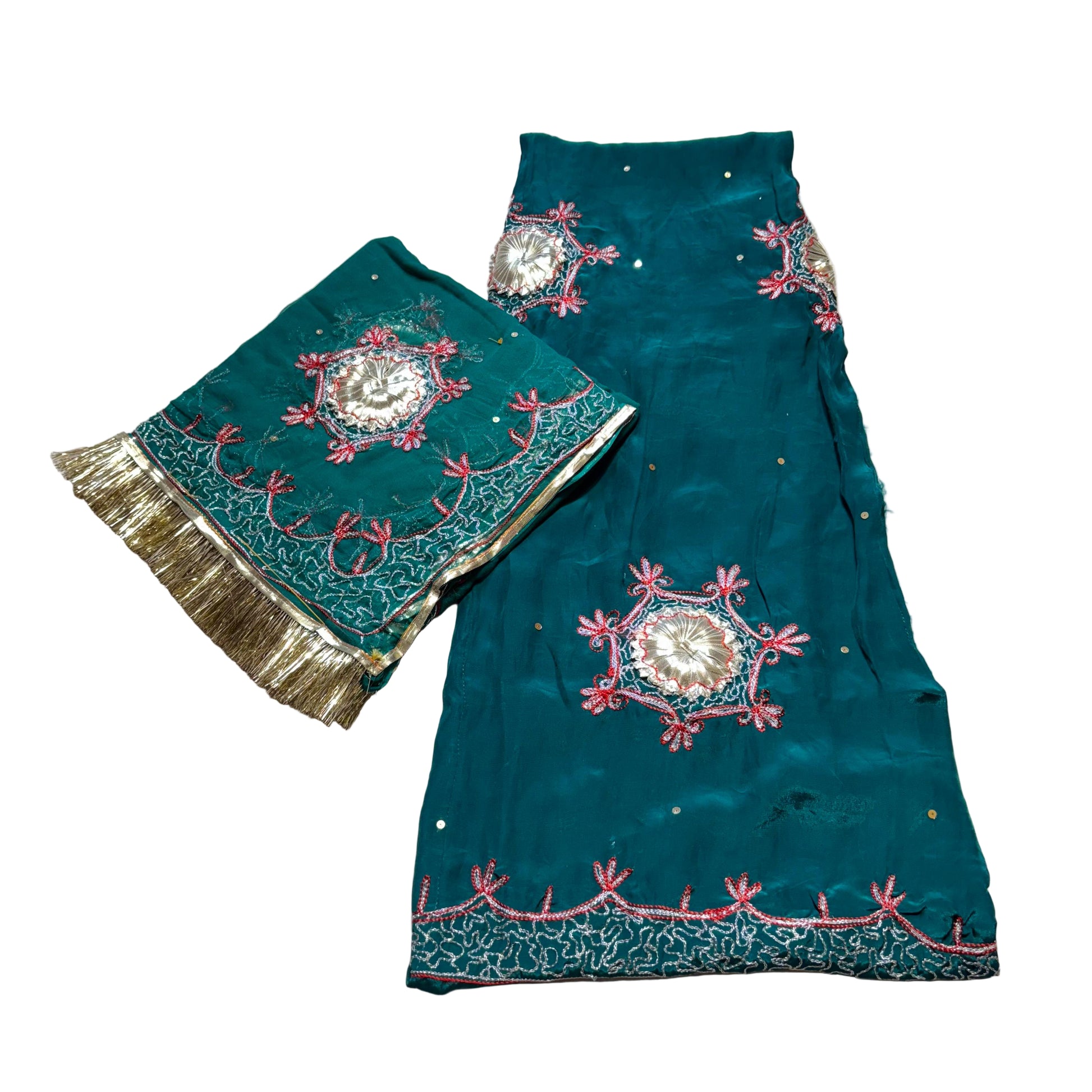 Teal fabric with intricate embroidery on a textured surface