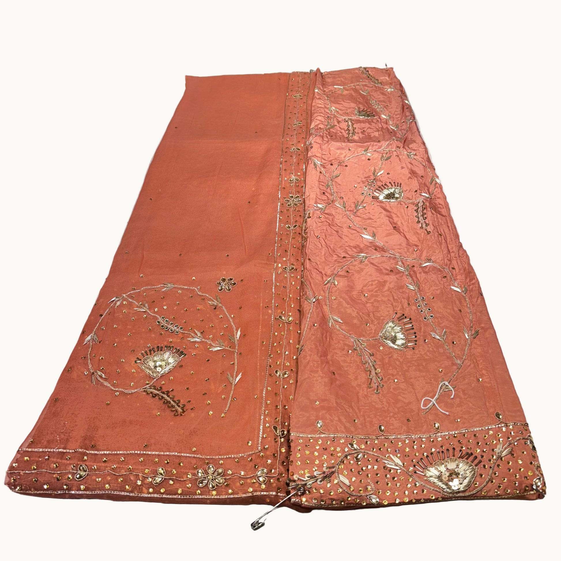 Decorative orange fabric with intricate gold embroidery on a white background