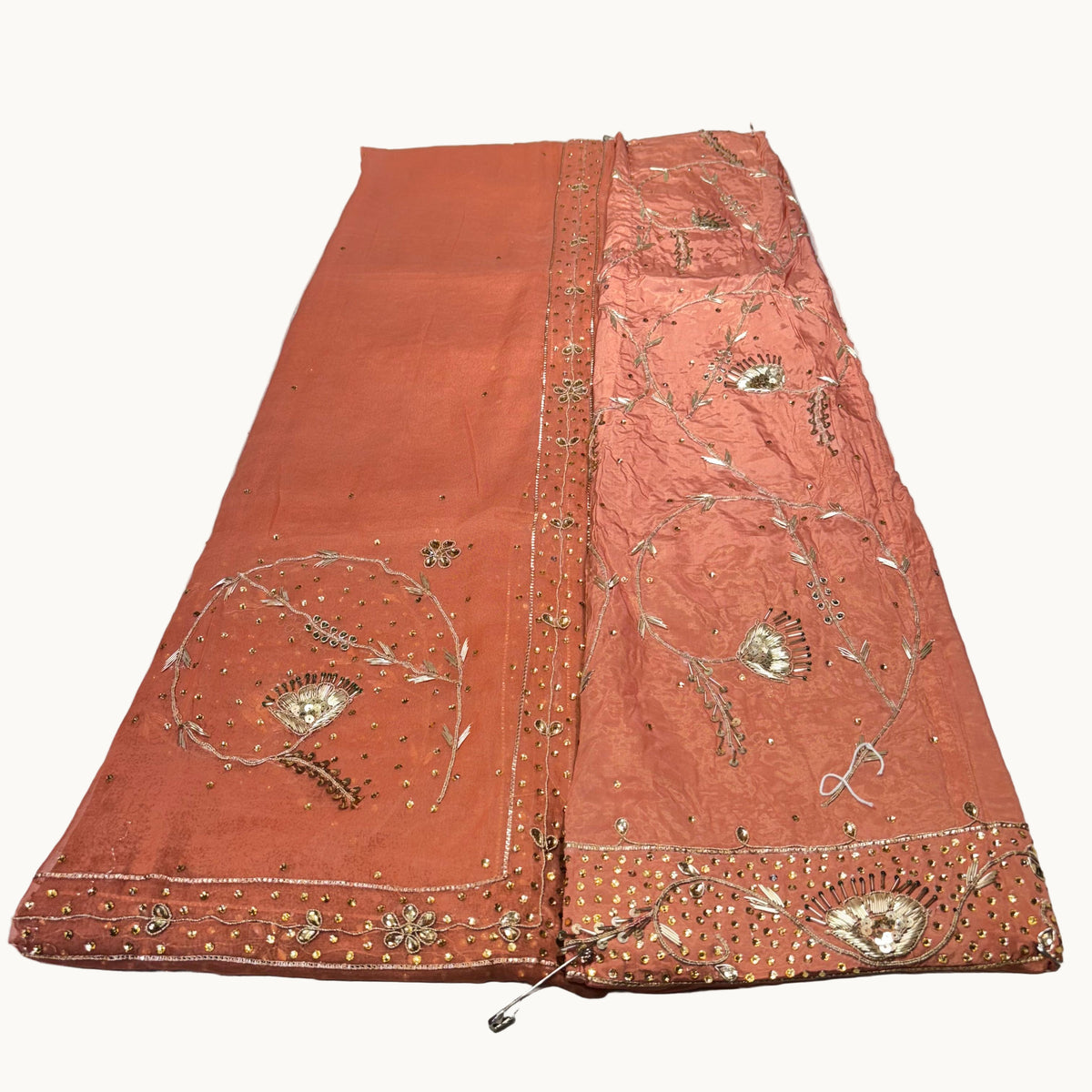 Decorative orange fabric with intricate gold embroidery on a white background