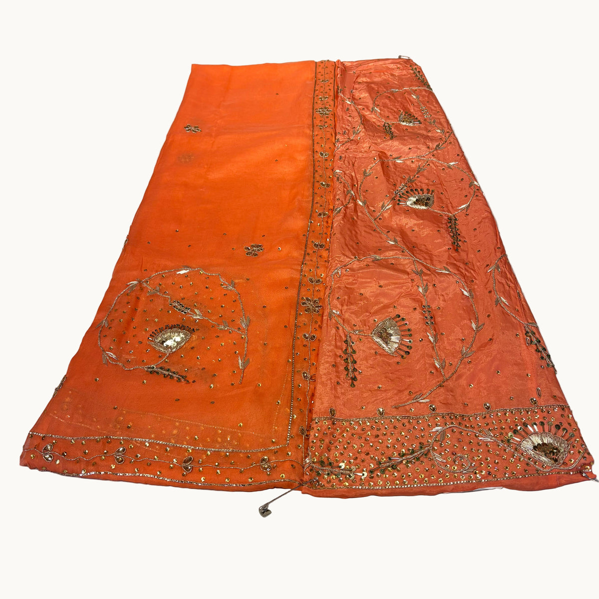 Orange fabric with gold embroidery on a white surface