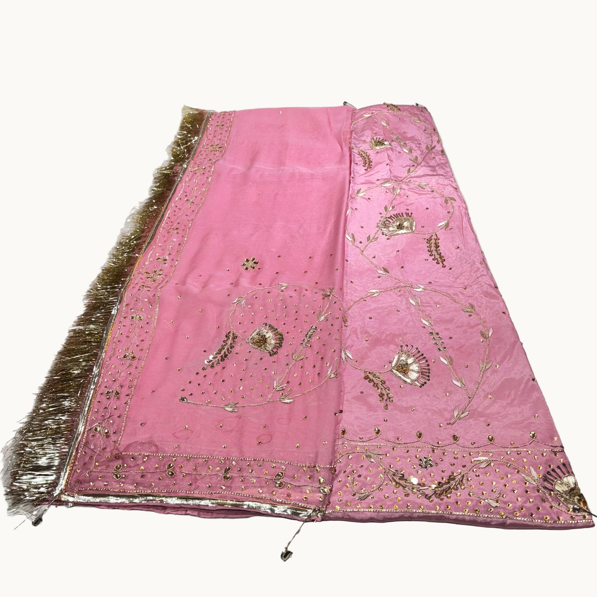 Pink embroidered fabric with gold details on a white background
