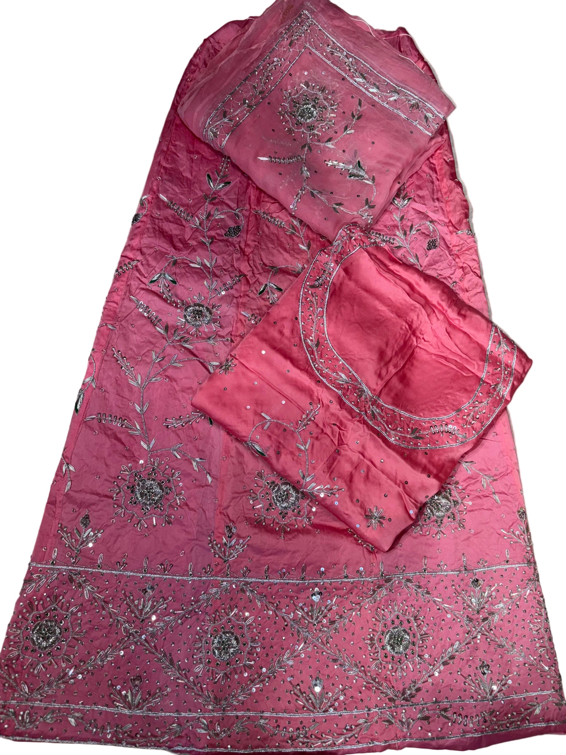 Pink embroidered fabric with intricate patterns on a beige surface