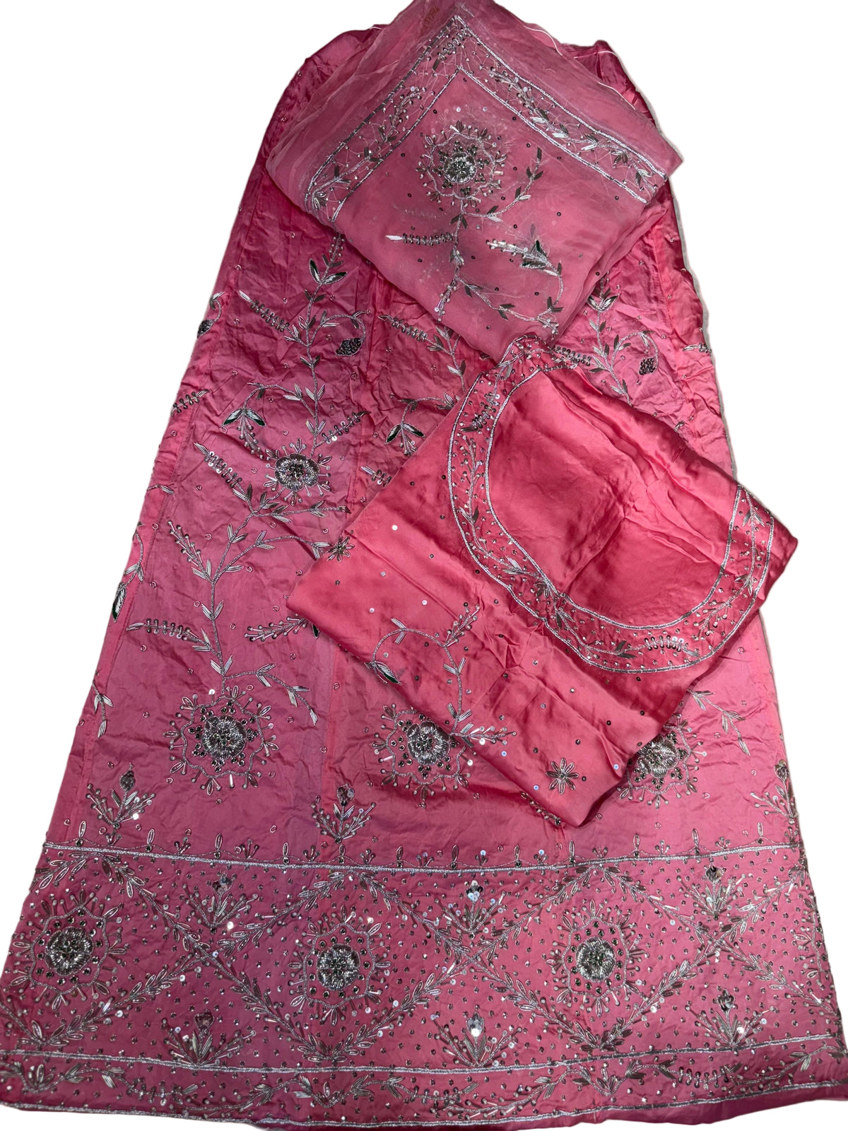 Pink embroidered fabric with intricate patterns on a beige surface