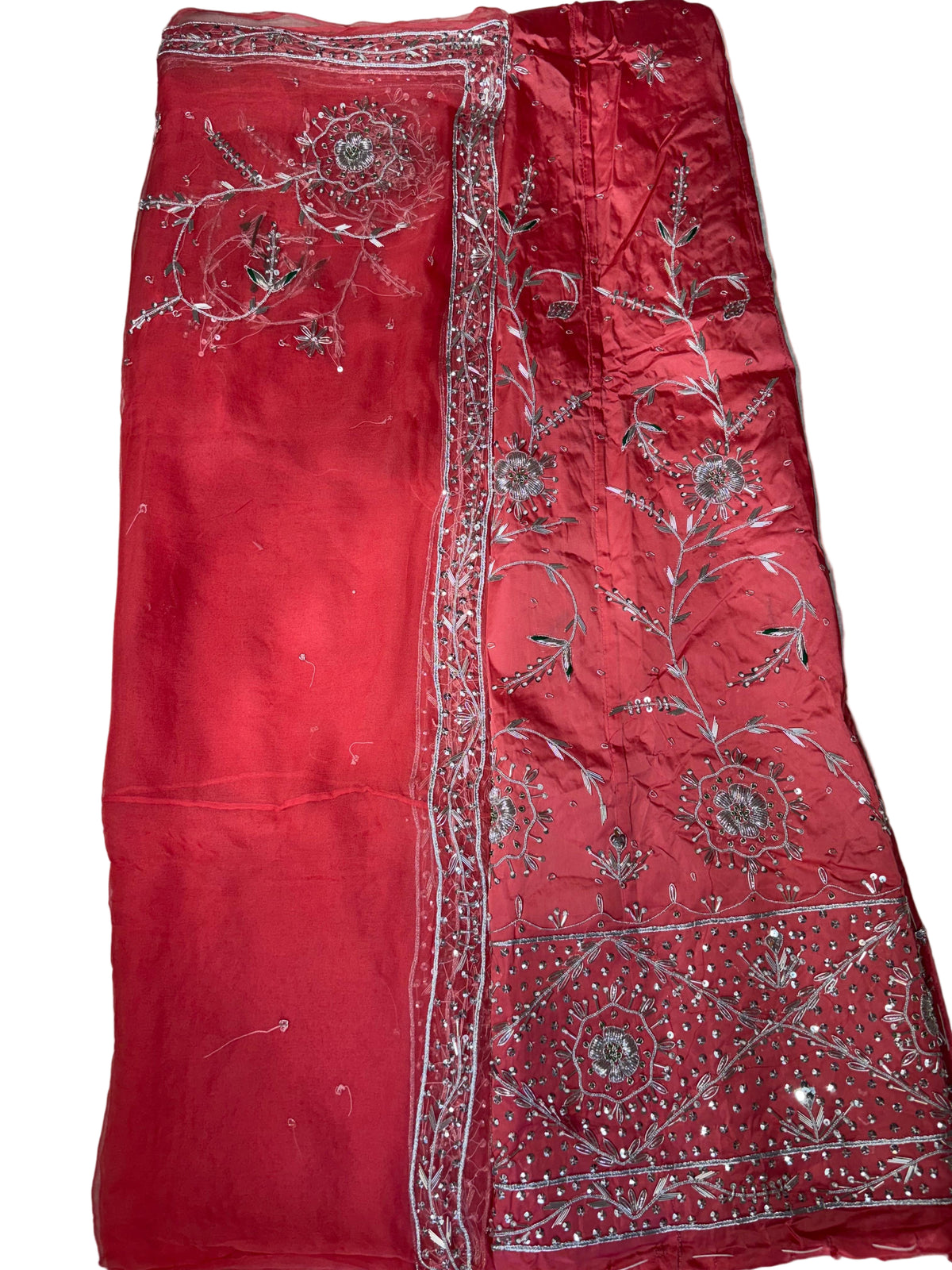 Red fabric with silver embroidery on a beige surface