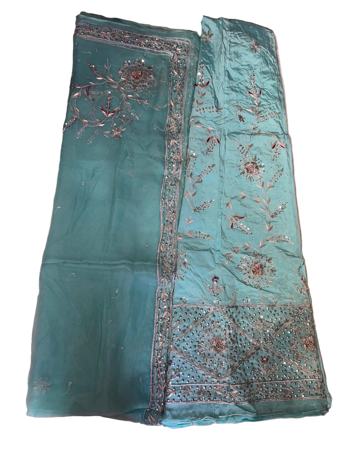 Teal fabric with intricate embroidery on a beige surface