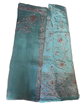 Teal fabric with intricate embroidery on a beige surface