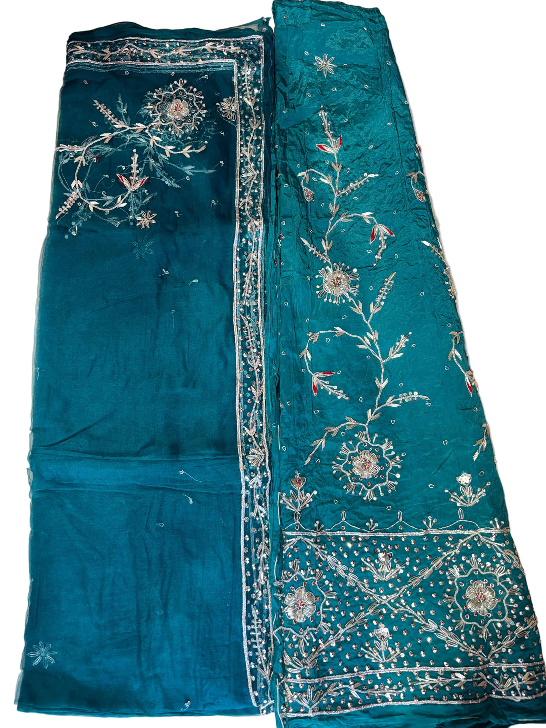 Teal fabric with intricate embroidery on a beige surface